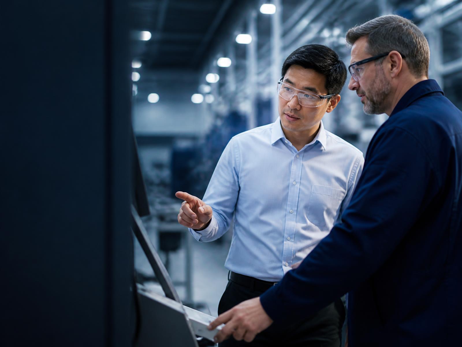 Manufacturing engineer and plant supervisor reviewing production equipment
